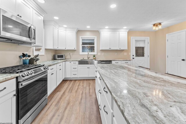 kitchen featuring white cabinetry, a sink, stainless steel appliances, recessed lighting, and light wood finished floors