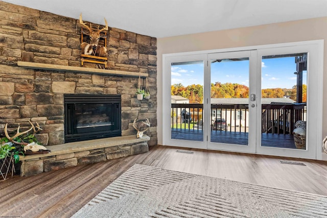 living room featuring visible vents, a stone fireplace, and wood finished floors