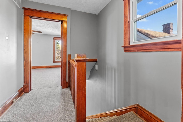 corridor featuring a textured ceiling and carpet floors