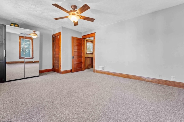 unfurnished bedroom with carpet flooring, a textured ceiling, and ceiling fan