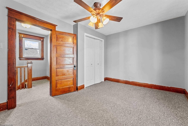 unfurnished bedroom featuring a textured ceiling, light colored carpet, a closet, and ceiling fan