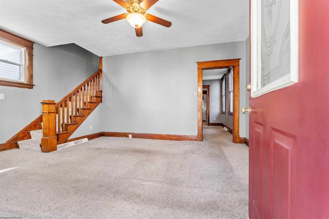 unfurnished living room with a textured ceiling, light colored carpet, and ceiling fan