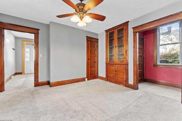 unfurnished bedroom featuring light carpet, a textured ceiling, and ceiling fan