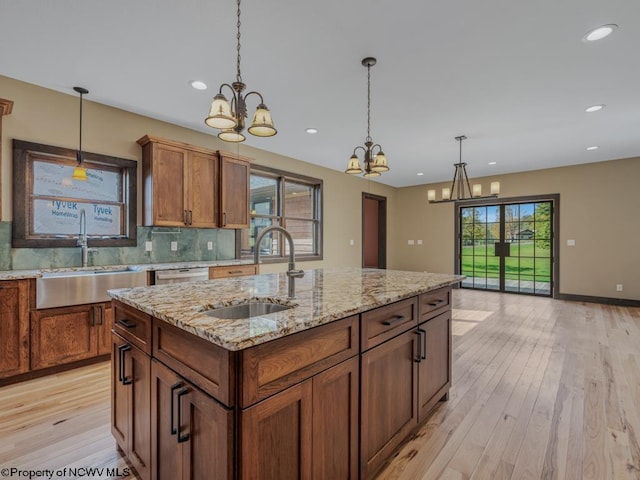 kitchen with sink, an island with sink, and light wood-type flooring