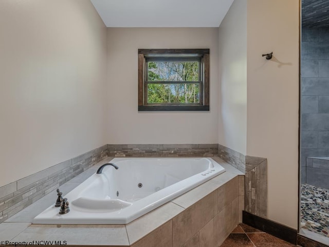 bathroom featuring a relaxing tiled tub and tile patterned flooring