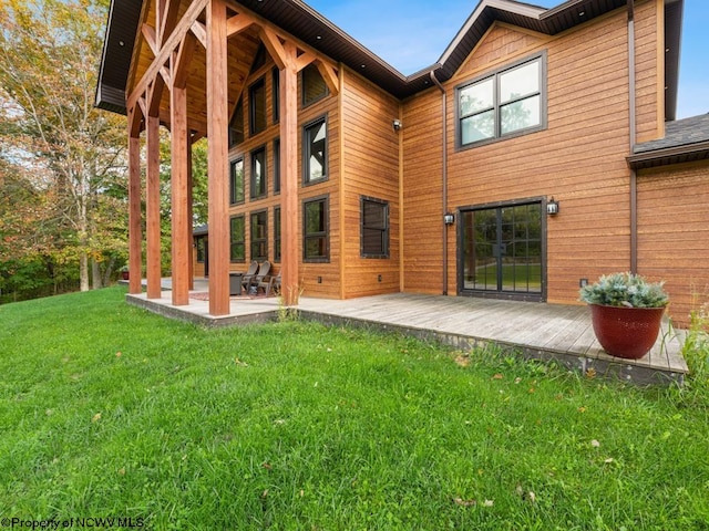 rear view of house with a patio area, a wooden deck, and a lawn