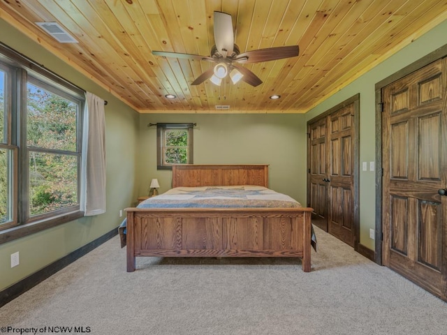 carpeted bedroom featuring wood ceiling, multiple windows, and ceiling fan