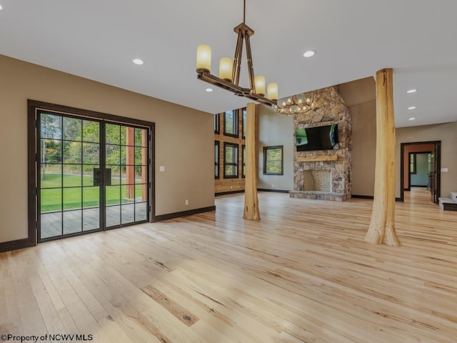 unfurnished living room featuring light hardwood / wood-style flooring, a notable chandelier, and a fireplace