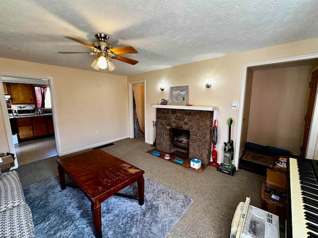 living room featuring a stone fireplace, a textured ceiling, dark colored carpet, and ceiling fan