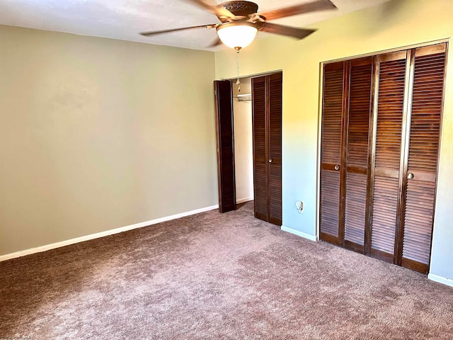 unfurnished bedroom with multiple closets, carpet flooring, and ceiling fan