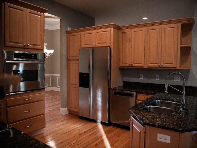 kitchen with dark stone countertops, light hardwood / wood-style floors, stainless steel appliances, and sink