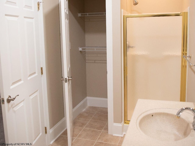 bathroom featuring a shower with shower door, tile patterned floors, and sink