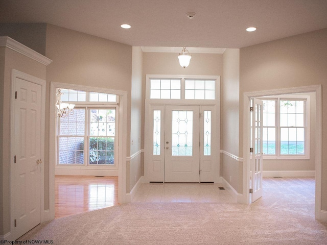 foyer with a chandelier, light carpet, and a towering ceiling