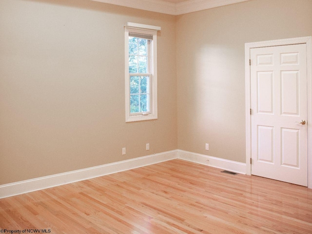 spare room with ornamental molding and light wood-type flooring