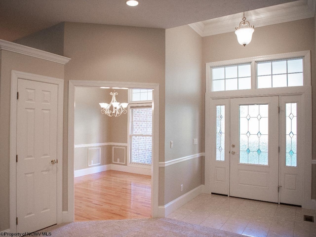 entryway with light hardwood / wood-style floors, a notable chandelier, and crown molding