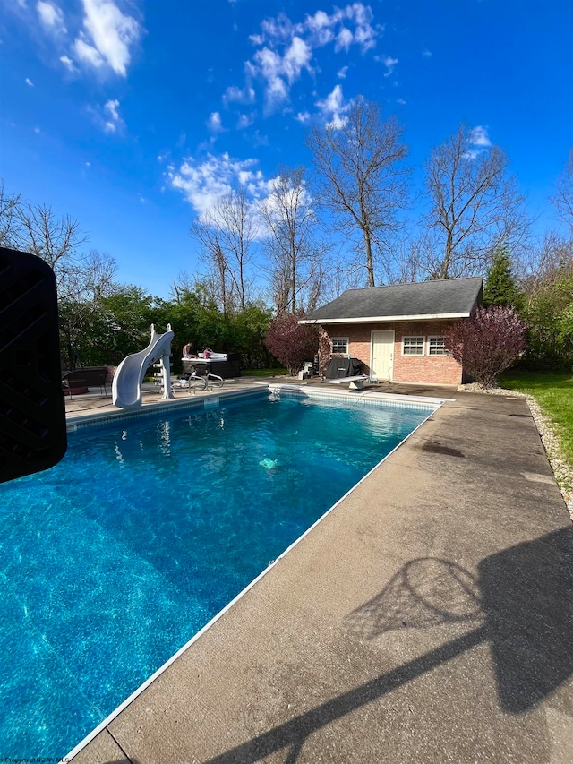 view of swimming pool with a water slide, a diving board, and a patio area