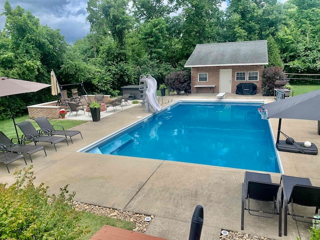 view of pool featuring a patio area, a water slide, an outdoor structure, and a diving board