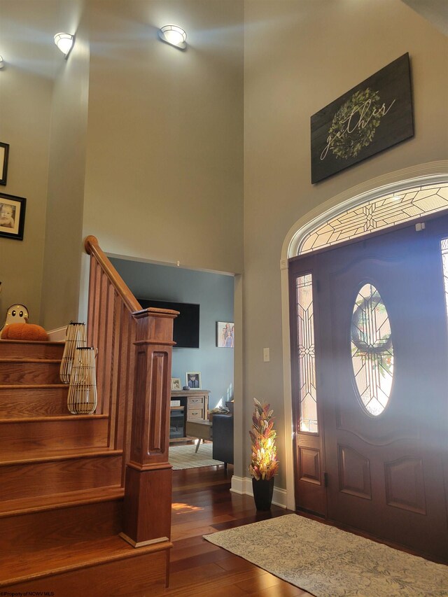 foyer entrance featuring hardwood / wood-style flooring and a towering ceiling