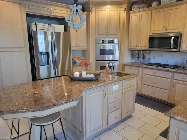 kitchen featuring stone countertops, an island with sink, stainless steel appliances, a kitchen bar, and tasteful backsplash