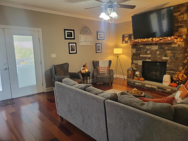 living room with french doors, a stone fireplace, ceiling fan, ornamental molding, and dark hardwood / wood-style floors