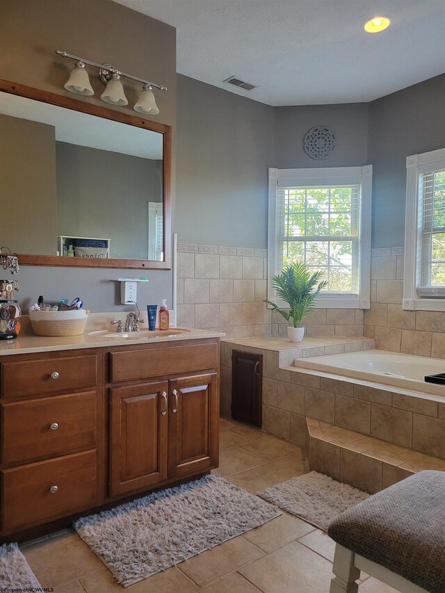 bathroom featuring vanity, a relaxing tiled tub, and tile patterned flooring