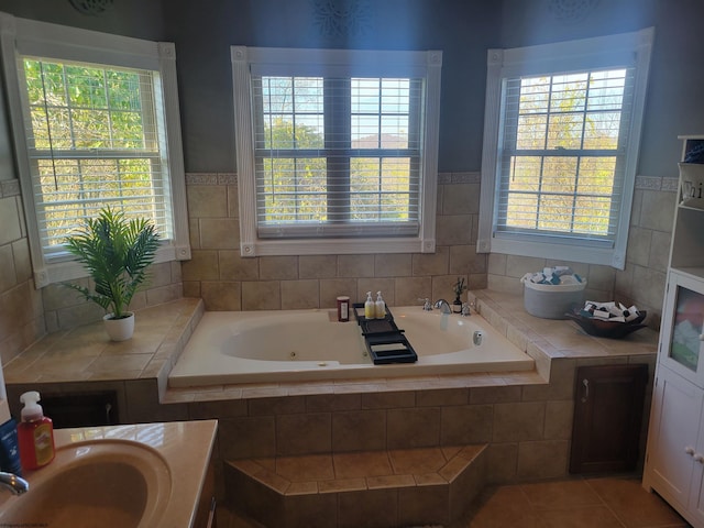 bathroom featuring vanity, a healthy amount of sunlight, tile patterned flooring, and tiled bath