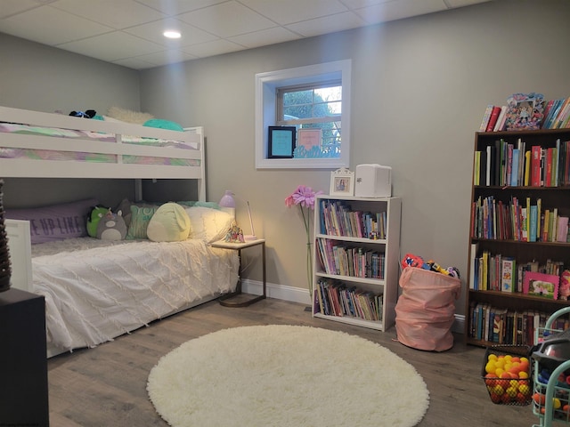 bedroom with a drop ceiling and wood-type flooring