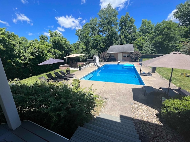 view of swimming pool featuring an outdoor structure, a water slide, and a patio