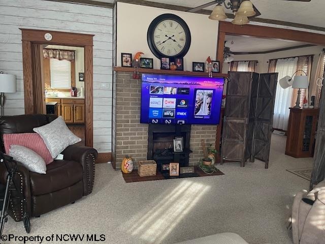 living room with wood walls, carpet floors, ceiling fan, and a brick fireplace