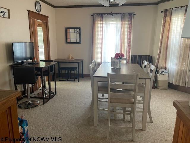 dining area featuring light carpet, ornamental molding, and ceiling fan