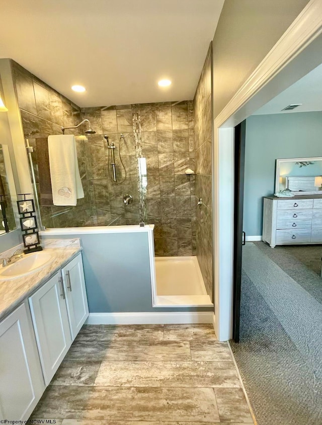 bathroom with vanity, wood-type flooring, and tiled shower