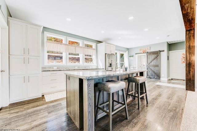 kitchen with a kitchen island, a barn door, and white cabinets