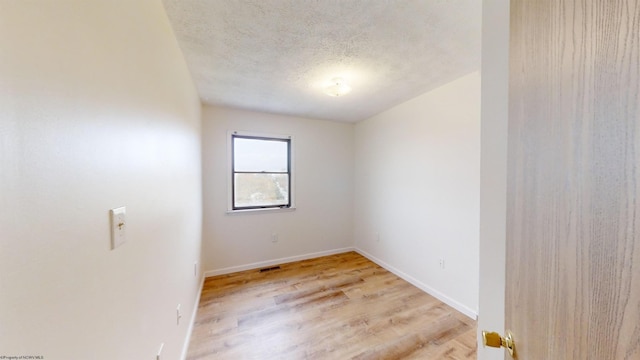 empty room with a textured ceiling and light wood-type flooring