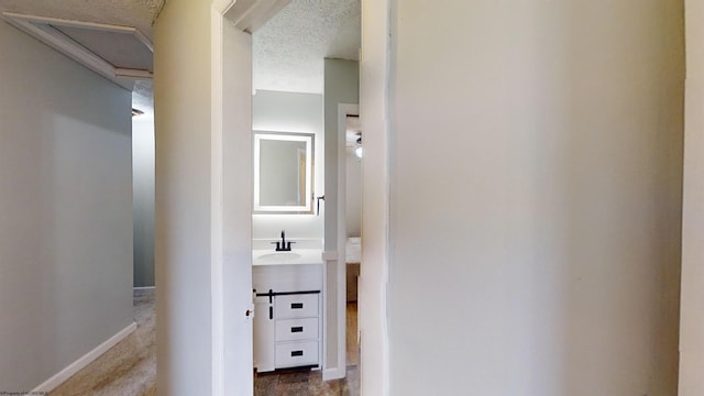 corridor with a textured ceiling, a barn door, and sink