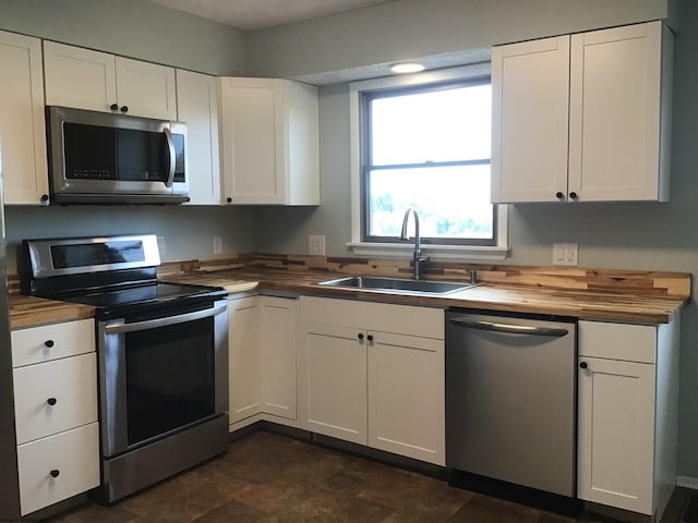 kitchen with sink, butcher block counters, stainless steel appliances, and white cabinets