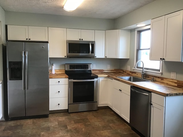 kitchen with wooden counters, sink, white cabinetry, and stainless steel appliances