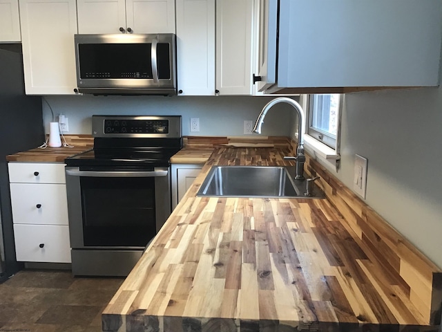 kitchen with sink, white cabinetry, stainless steel appliances, and wood counters