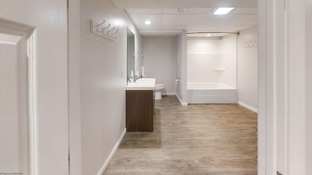 full bathroom with toilet, shower / tub combination, hardwood / wood-style floors, a drop ceiling, and vanity