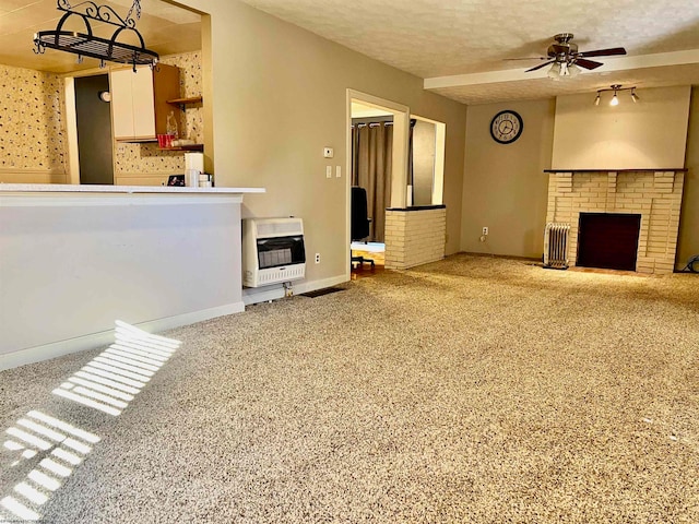 unfurnished living room featuring a fireplace, heating unit, carpet flooring, a textured ceiling, and ceiling fan