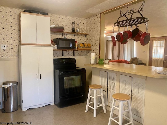 kitchen with white cabinets, black appliances, and a kitchen bar