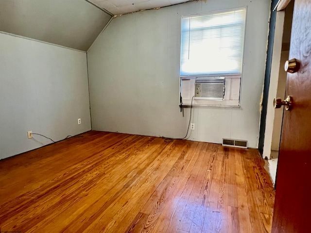 additional living space with vaulted ceiling, cooling unit, and light wood-type flooring