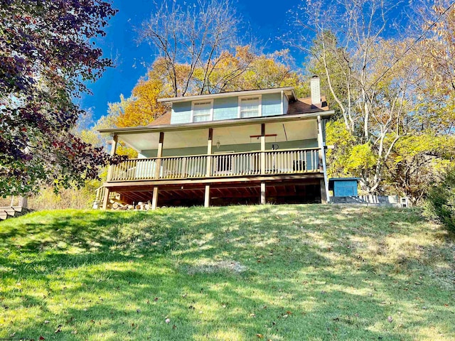 rear view of property with ceiling fan and a lawn