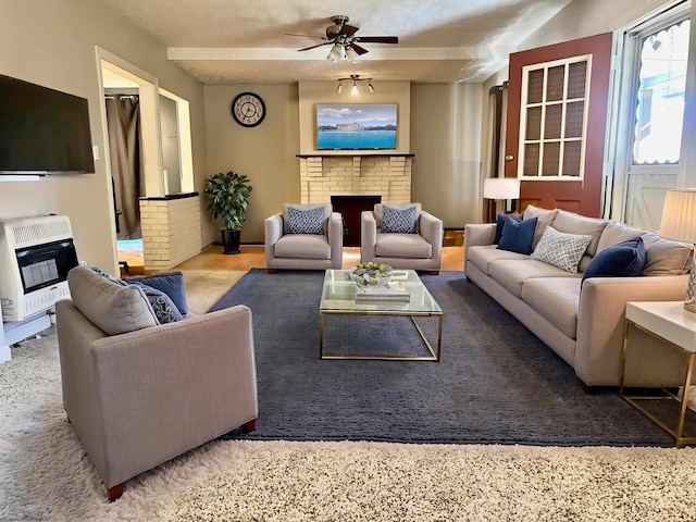 carpeted living room featuring ceiling fan, heating unit, and a brick fireplace