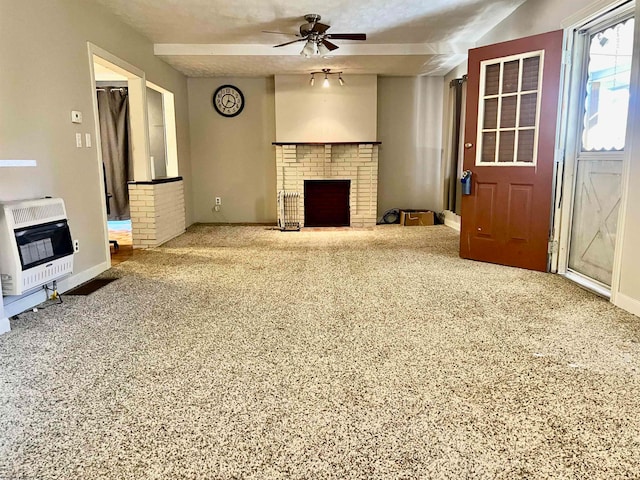 unfurnished living room featuring heating unit, carpet, ceiling fan, a textured ceiling, and a fireplace