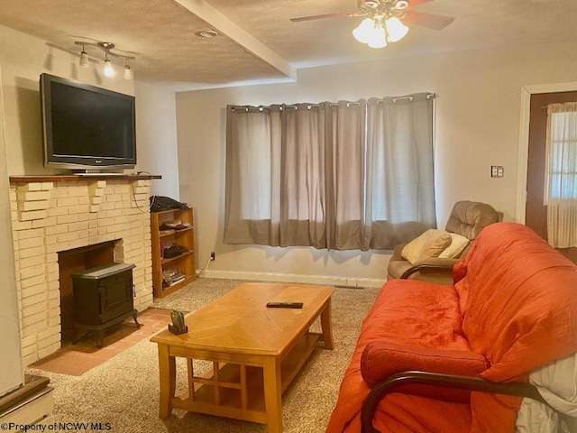 carpeted living room featuring a textured ceiling, a wood stove, and ceiling fan