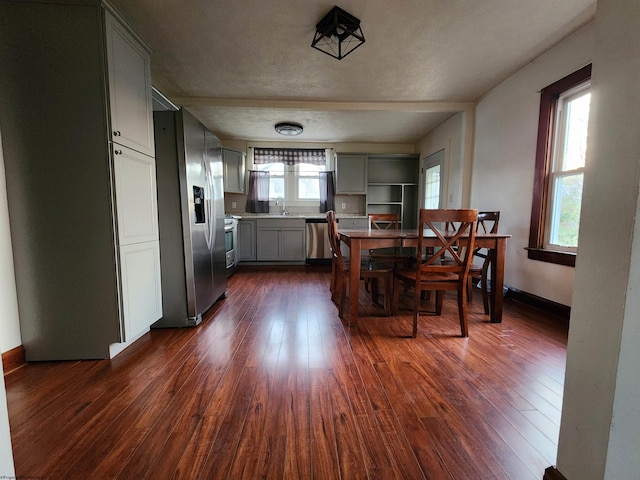 dining space featuring a textured ceiling, a healthy amount of sunlight, sink, and dark wood-type flooring