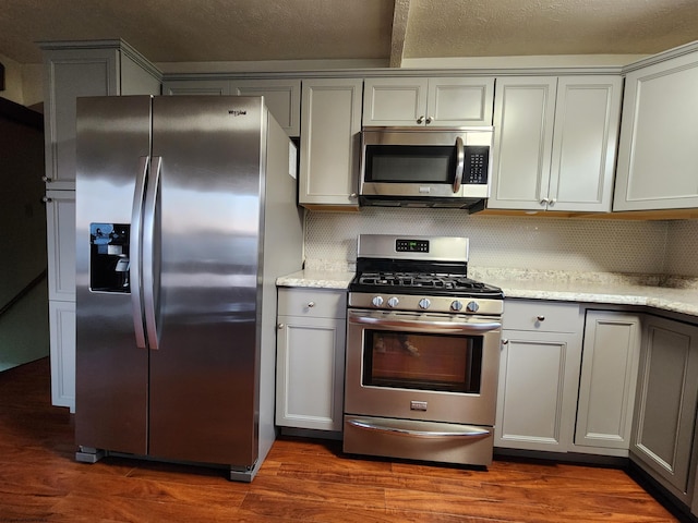 kitchen featuring appliances with stainless steel finishes, dark hardwood / wood-style floors, backsplash, and gray cabinetry