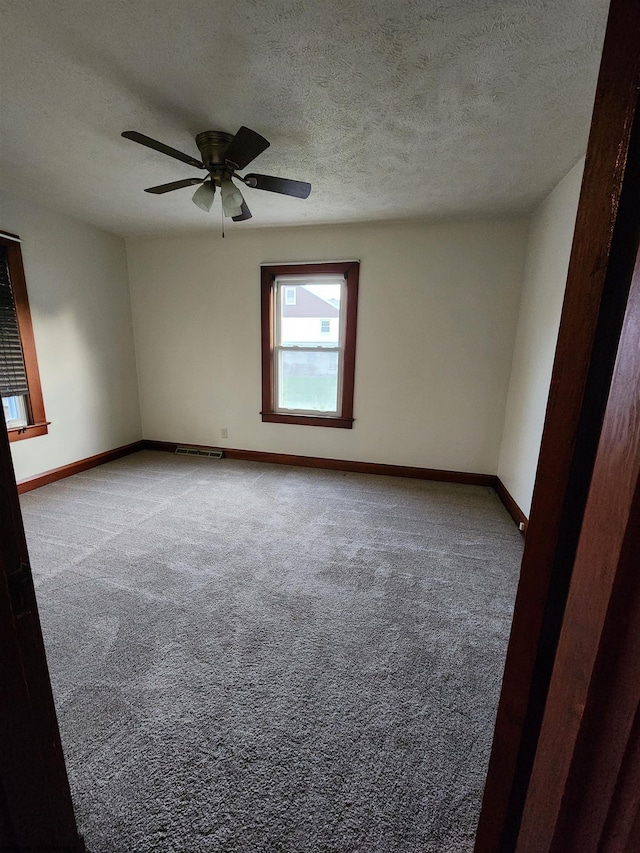 spare room with ceiling fan, a textured ceiling, and carpet floors