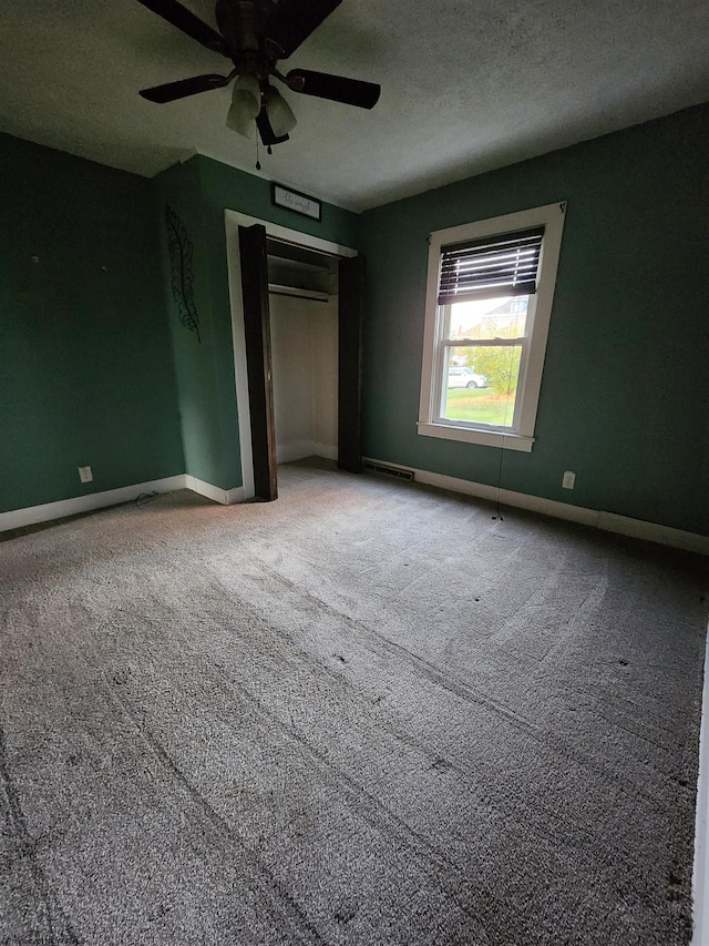 unfurnished bedroom featuring carpet, a textured ceiling, a closet, and ceiling fan