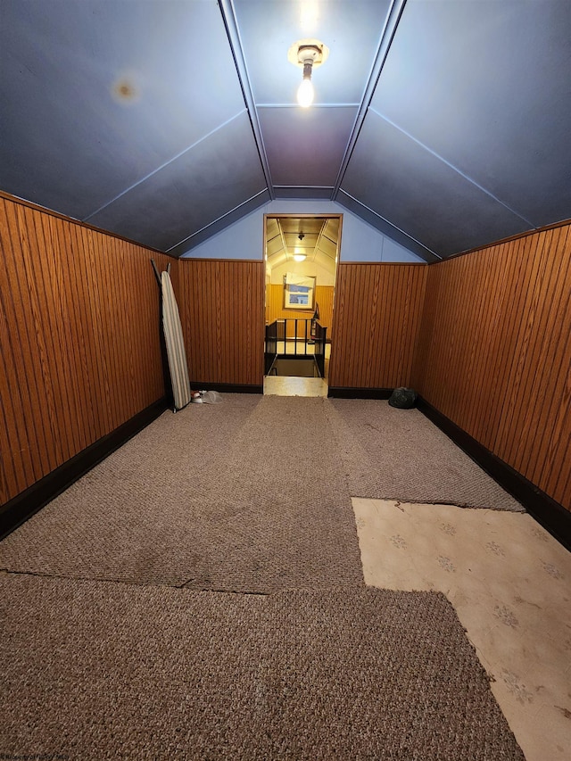 additional living space with wooden walls, carpet, and vaulted ceiling